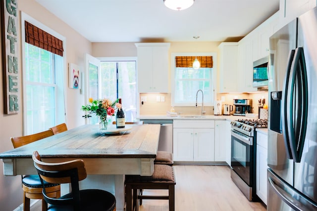 107 Artist Falls Rd, Conway, NH 03860 - kitchen featuring stainless steel appliances, a sink, a breakfast bar area, white cabinetry, and light wood finished floors