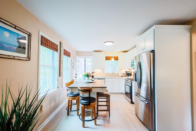 107 Artist Falls Rd, Conway, NH 03860 - kitchen with appliances with stainless steel finishes, a breakfast bar area, light wood-style flooring, light countertops, and white cabinets
