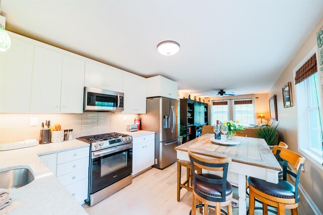 107 Artist Falls Rd, Conway, NH 03860 - kitchen featuring stainless steel appliances, light countertops, light wood-type flooring, white cabinetry, and decorative backsplash