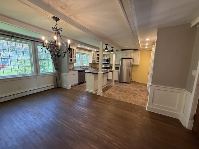 154B Main St, Kingston, NH 03848 - kitchen with stainless steel appliances, a baseboard heating unit, a chandelier, white cabinets, and dark wood-type flooring