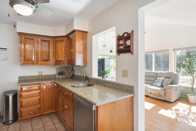 49 Morgan St, Burlington, VT 05408 - kitchen featuring stainless steel dishwasher, a sink, brown cabinetry, light stone countertops, and a ceiling fan