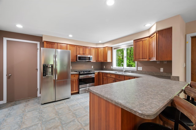 11 Sledding Hill Ln, Lee, NH 03861 - kitchen with appliances with stainless steel finishes, a sink, brown cabinets, a breakfast bar area, and a peninsula