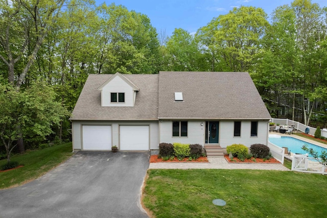 11 Sledding Hill Ln, Lee, NH 03861 - cape cod home featuring asphalt driveway, an outdoor pool, roof with shingles, an attached garage, and view of scattered trees