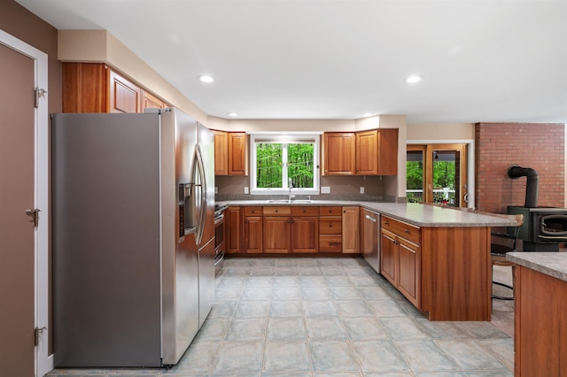 11 Sledding Hill Ln, Lee, NH 03861 - kitchen with appliances with stainless steel finishes, a sink, a peninsula, a wood stove, and brown cabinets