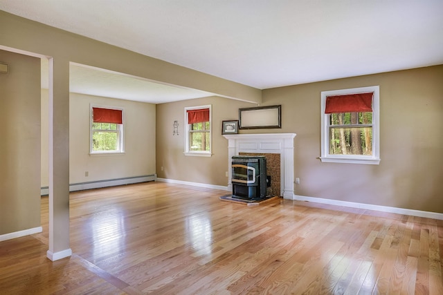 185 Whitford St, Manchester, NH 03104 - unfurnished living room featuring a wood stove, light wood-type flooring, baseboard heating, and baseboards