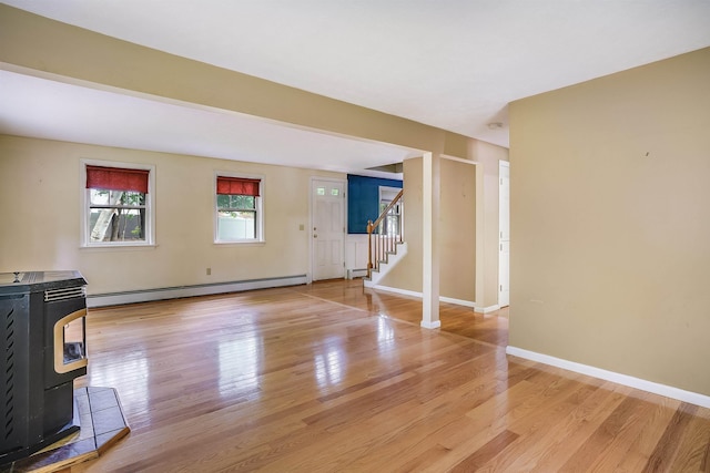 185 Whitford St, Manchester, NH 03104 - unfurnished living room with baseboard heating, a wood stove, light wood-style floors, and stairway