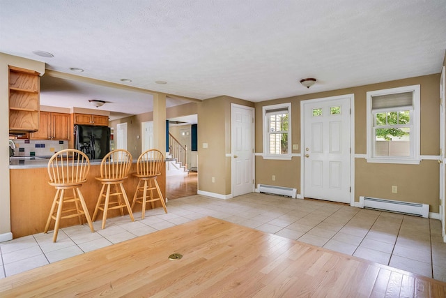 185 Whitford St, Manchester, NH 03104 - entrance foyer with a baseboard radiator, light tile patterned floors, healthy amount of natural light, and a textured ceiling