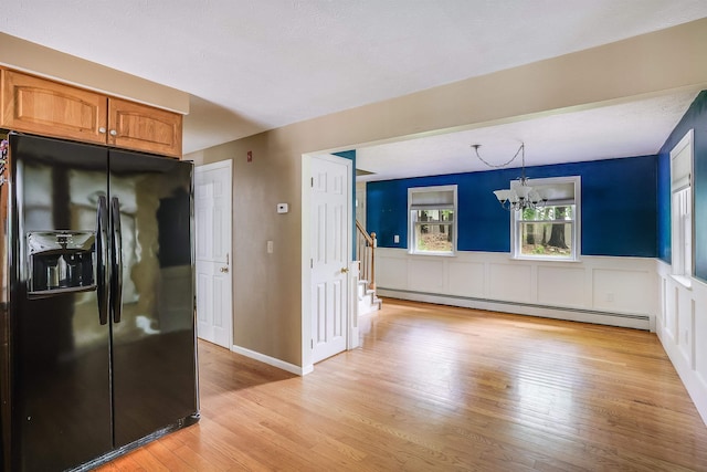 185 Whitford St, Manchester, NH 03104 - kitchen with black fridge, baseboard heating, light wood finished floors, brown cabinetry, and a chandelier