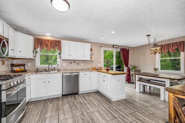 28 Hardy Rd, Londonderry, NH 03053 - kitchen with appliances with stainless steel finishes, a sink, a peninsula, wood finish floors, and white cabinets