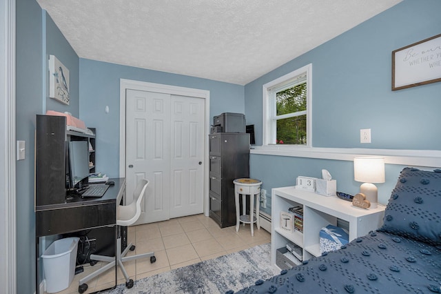 28 Hardy Rd, Londonderry, NH 03053 - bedroom with a desk, light tile patterned floors, a textured ceiling, a baseboard heating unit, and a closet
