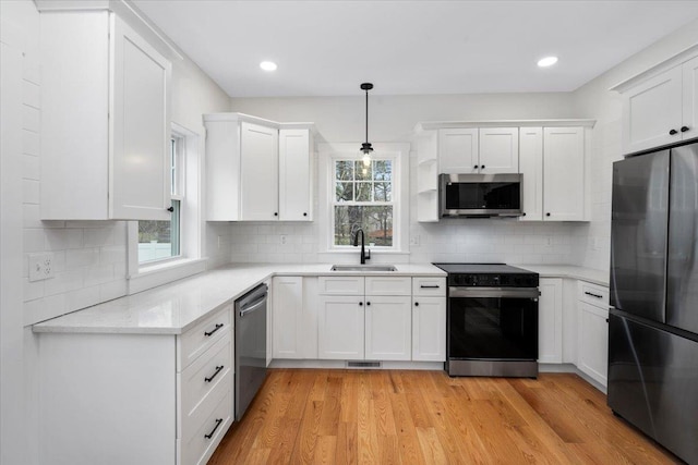 140 S Mast St, Goffstown, NH 03045 - kitchen with stainless steel appliances, a sink, white cabinets, light wood-style floors, and backsplash
