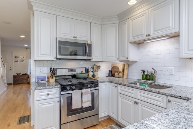 37 Highland Ave Unit 4, Derry, NH 03038 - kitchen with stainless steel appliances, a sink, white cabinets, decorative backsplash, and recessed lighting