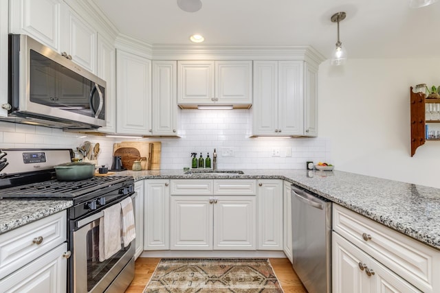 37 Highland Ave Unit 4, Derry, NH 03038 - kitchen with stainless steel appliances, a sink, white cabinetry, light stone counters, and decorative backsplash