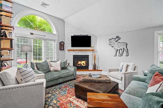 31 Henderson Rd Unit 17, Gilford, NH 03249 - living room featuring vaulted ceiling and a warm lit fireplace