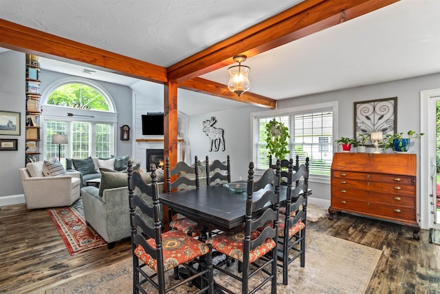 31 Henderson Rd Unit 17, Gilford, NH 03249 - dining area with wood finished floors, beam ceiling, baseboards, and a glass covered fireplace