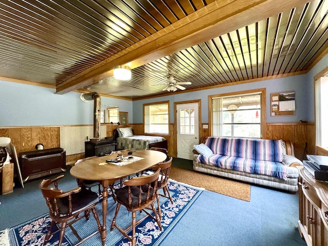 106 Philbrook Rd, Pittsburg, NH 03592 - dining room featuring carpet flooring, wood walls, a wainscoted wall, a wood stove, and a ceiling fan
