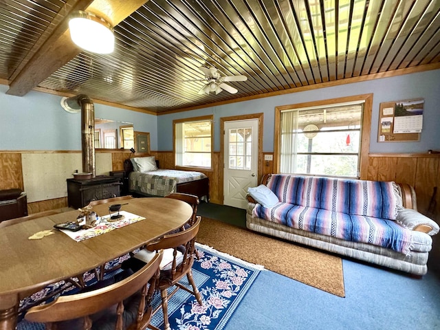 106 Philbrook Rd, Pittsburg, NH 03592 - carpeted living area with a wainscoted wall, wooden walls, wooden ceiling, ceiling fan, and a wood stove