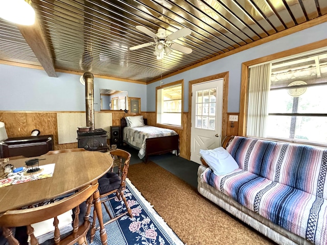 106 Philbrook Rd, Pittsburg, NH 03592 - bedroom with wainscoting, wood walls, carpet flooring, a wood stove, and a ceiling fan