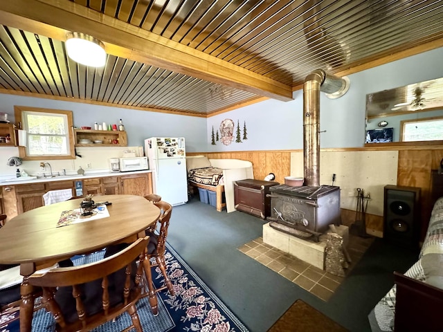 106 Philbrook Rd, Pittsburg, NH 03592 - kitchen with white appliances, a wood stove, wainscoting, carpet floors, and wood walls