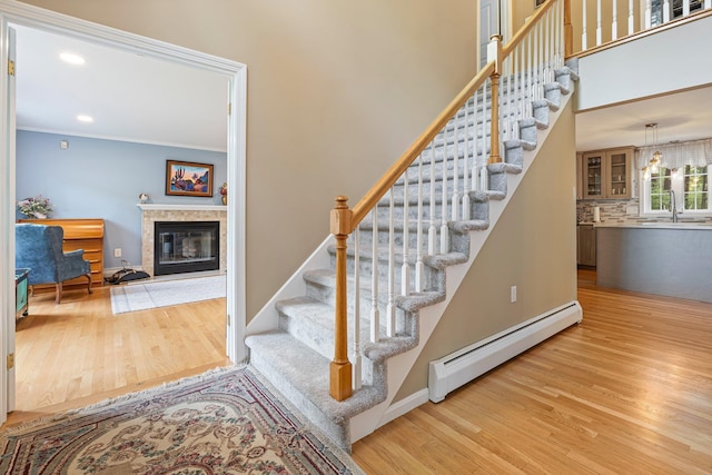 15 Fox Meadow Ln, Merrimack, NH 03054 - stairway with a baseboard heating unit, wood finished floors, a tiled fireplace, baseboards, and recessed lighting