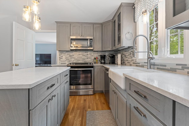 15 Fox Meadow Ln, Merrimack, NH 03054 - kitchen featuring appliances with stainless steel finishes, gray cabinetry, a sink, backsplash, and light wood-type flooring