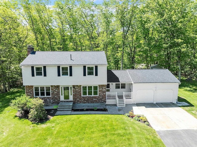 11 Woodhenge Cir, Londonderry, NH 03053 - view of front of house featuring a chimney, a garage, brick siding, and driveway