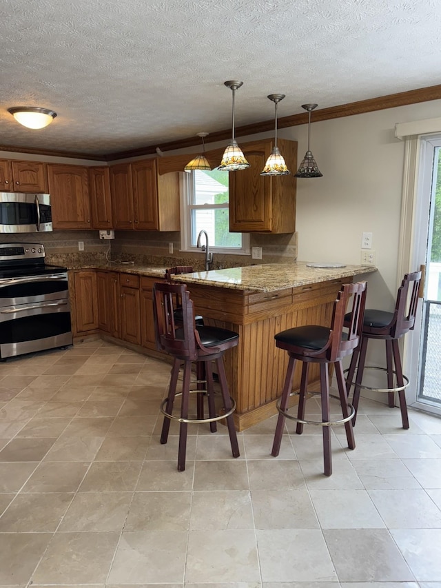 9 Quarry Rd, Hampstead, NH 03841 - kitchen featuring stainless steel appliances, brown cabinets, a breakfast bar area, a textured ceiling, and a sink