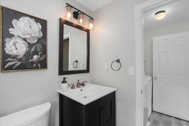 37 Level St, Merrimack, NH 03054 - bathroom featuring vanity, toilet, wood finished floors, and washing machine and dryer
