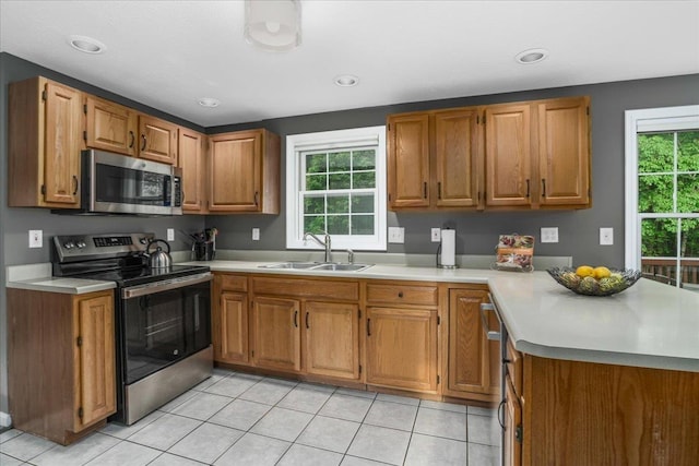 37 Level St, Merrimack, NH 03054 - kitchen featuring stainless steel appliances, a sink, light countertops, brown cabinets, and a peninsula