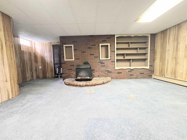 366 S Main St, Concord, NH 03301 - unfurnished living room with wooden walls, a wood stove, carpet flooring, a drop ceiling, and built in shelves