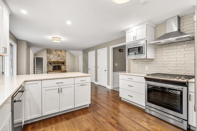 47 Blossom Rd, Windham, NH 03087 - kitchen with appliances with stainless steel finishes, wall chimney range hood, dark wood-type flooring, backsplash, and white cabinetry