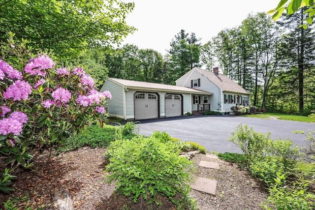 144 Whitten Rd, Milford, NH 03055 - view of front of house featuring a garage, driveway, a chimney, and view of wooded area