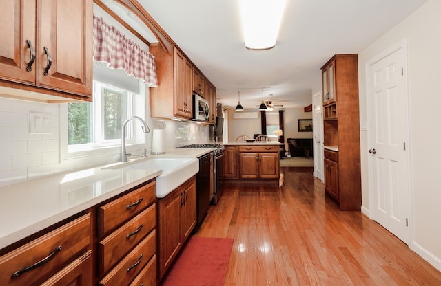 144 Whitten Rd, Milford, NH 03055 - kitchen featuring stainless steel microwave, a peninsula, a sink, wood finished floors, and brown cabinetry