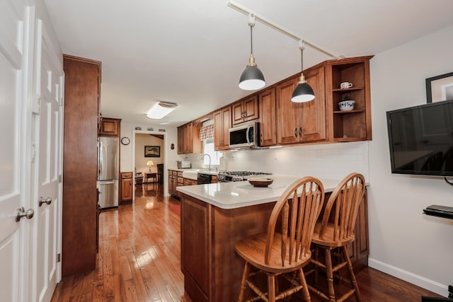 144 Whitten Rd, Milford, NH 03055 - kitchen with appliances with stainless steel finishes, brown cabinets, a peninsula, dark wood finished floors, and a breakfast bar area