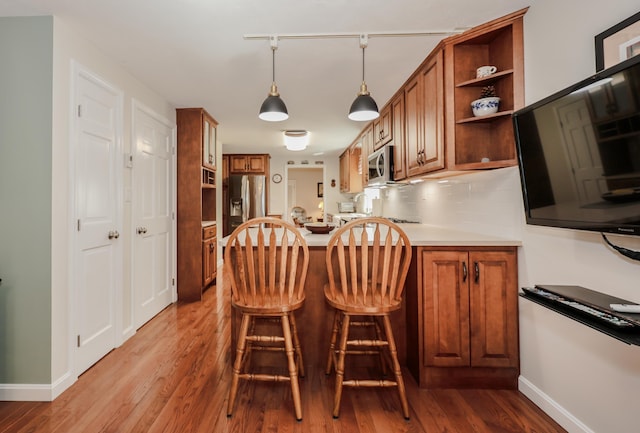 144 Whitten Rd, Milford, NH 03055 - kitchen with appliances with stainless steel finishes, brown cabinets, open shelves, a peninsula, and baseboards