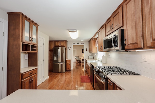144 Whitten Rd, Milford, NH 03055 - kitchen featuring appliances with stainless steel finishes, light wood-type flooring, backsplash, light countertops, and glass insert cabinets