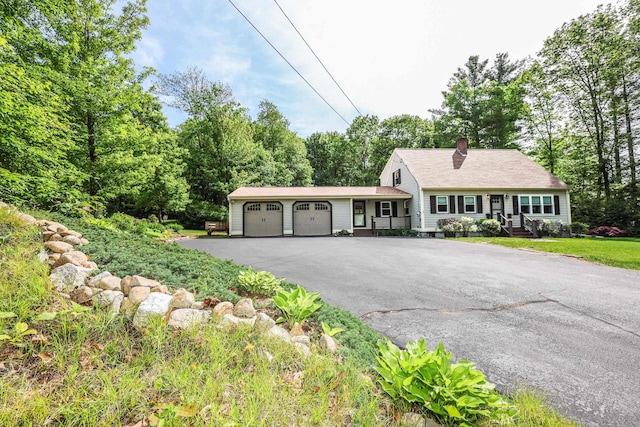 144 Whitten Rd, Milford, NH 03055 - view of front of home featuring a garage, driveway, a chimney, and view of wooded area