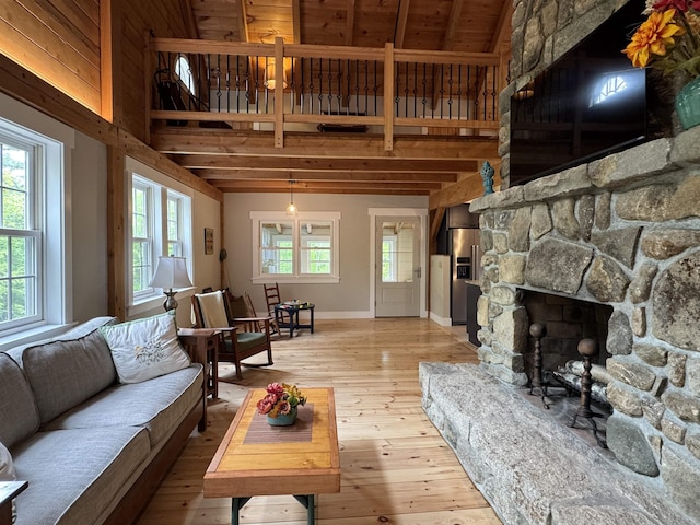 689 Hard Scrabble Rd, Sweden, ME 04008 - living room with a stone fireplace, light wood-type flooring, baseboards, and beam ceiling