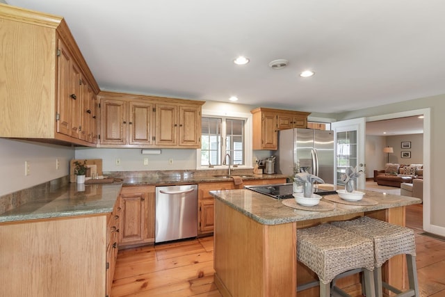 19 Cambridge Rd, Hampstead, NH 03841 - kitchen with stainless steel appliances, a breakfast bar, a sink, light wood-style flooring, and a kitchen island