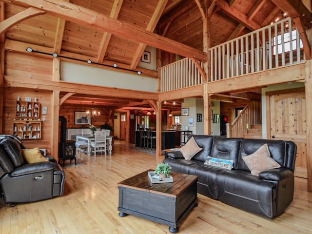 93 Rowell Hill Rd, New London, NH 03257 - living area with high vaulted ceiling, wood-type flooring, stairway, wood walls, and wood ceiling with exposed beams
