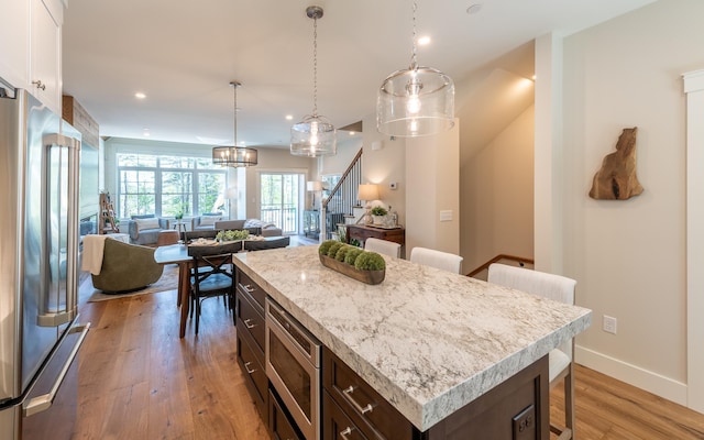 60 White Oaks Rd Unit 26, Laconia, NH 03246 - kitchen featuring stainless steel appliances, a breakfast bar, dark brown cabinetry, light wood-style floors, and baseboards