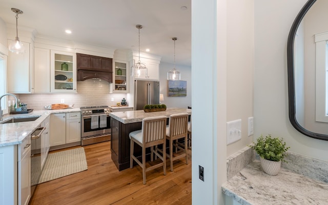 60 White Oaks Rd Unit 26, Laconia, NH 03246 - kitchen featuring stainless steel appliances, a sink, light wood-type flooring, backsplash, and a kitchen bar