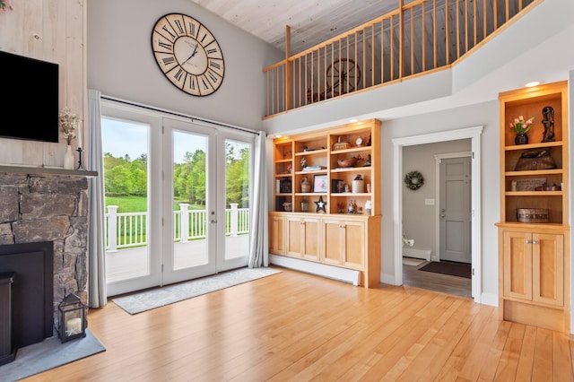 345 Williams Rd, Littleton, NH 03561 - unfurnished living room with high vaulted ceiling, a baseboard radiator, french doors, a fireplace, and hardwood / wood-style floors