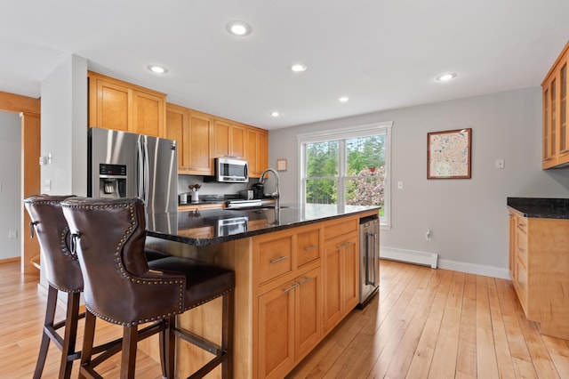 345 Williams Rd, Littleton, NH 03561 - kitchen with stainless steel appliances, a sink, baseboards, a kitchen breakfast bar, and light wood-style flooring