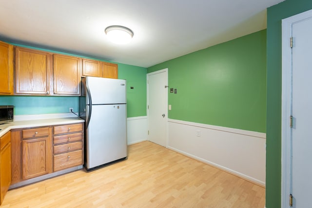 101 E Broadway Rd Unit 1, Derry, NH 03038 - kitchen featuring appliances with stainless steel finishes, light wood-style floors, brown cabinetry, and light countertops