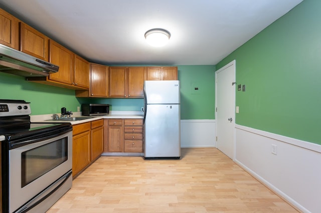 101 E Broadway Rd Unit 1, Derry, NH 03038 - kitchen featuring stainless steel appliances, under cabinet range hood, light wood-style flooring, light countertops, and brown cabinetry