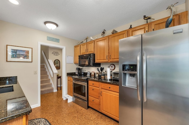 51 Cardinal Dr Unit B, Laconia, NH 03246 - kitchen with stainless steel appliances, baseboards, dark stone countertops, a textured ceiling, and light flooring