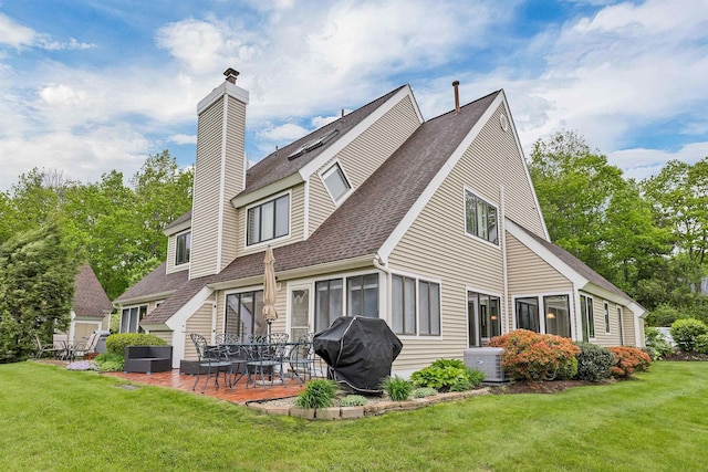 51 Cardinal Dr Unit B, Laconia, NH 03246 - back of property featuring roof with shingles, a patio area, a chimney, and a lawn