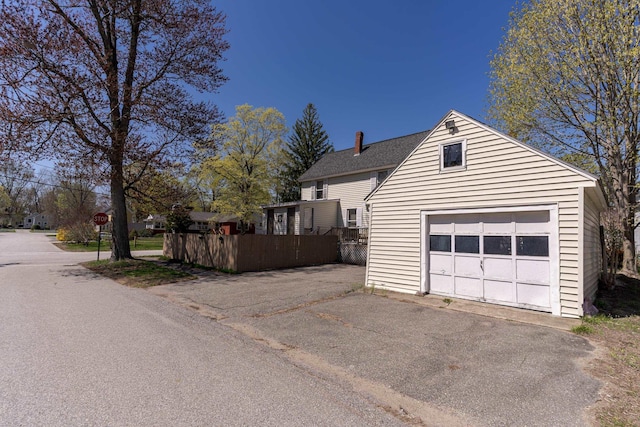 12 Harvard St, Exeter, NH 03862 - view of home's exterior with driveway, an outdoor structure, a chimney, and roof with shingles