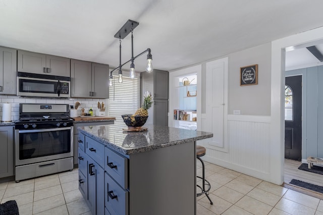 12 Harvard St, Exeter, NH 03862 - kitchen featuring appliances with stainless steel finishes, gray cabinetry, light tile patterned flooring, and a wainscoted wall